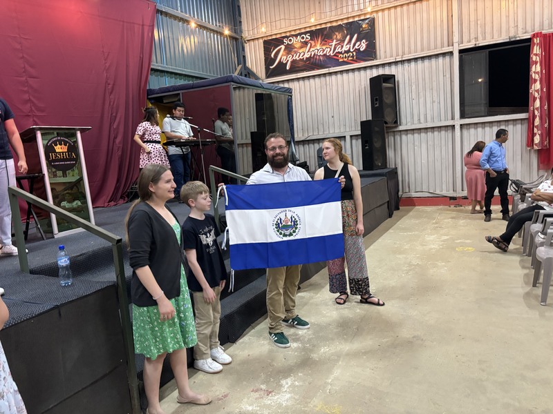 A group standing by a stage, holding a flag