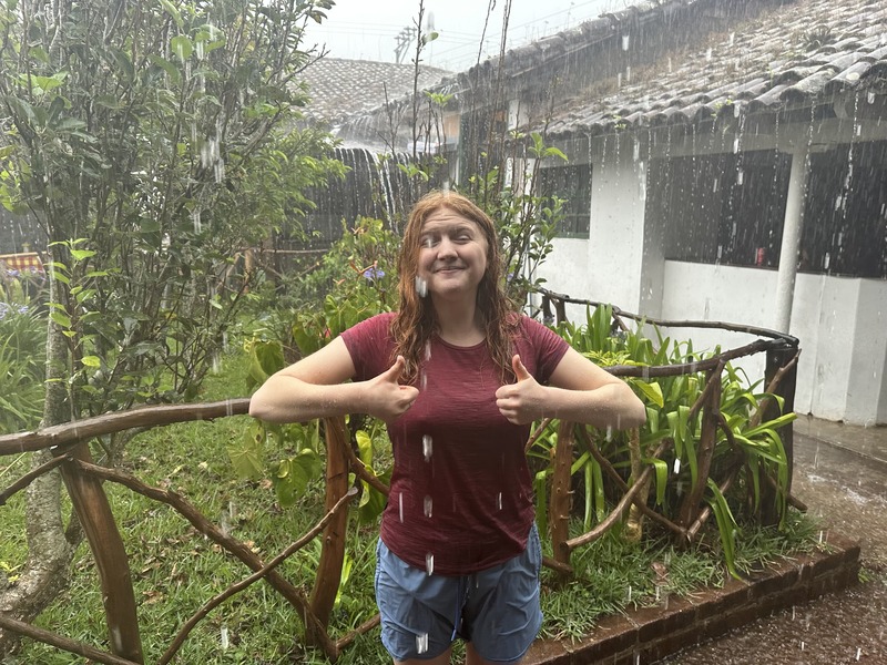 A girl giving two thumbs up in a red shirt, in the rain, in el salvador